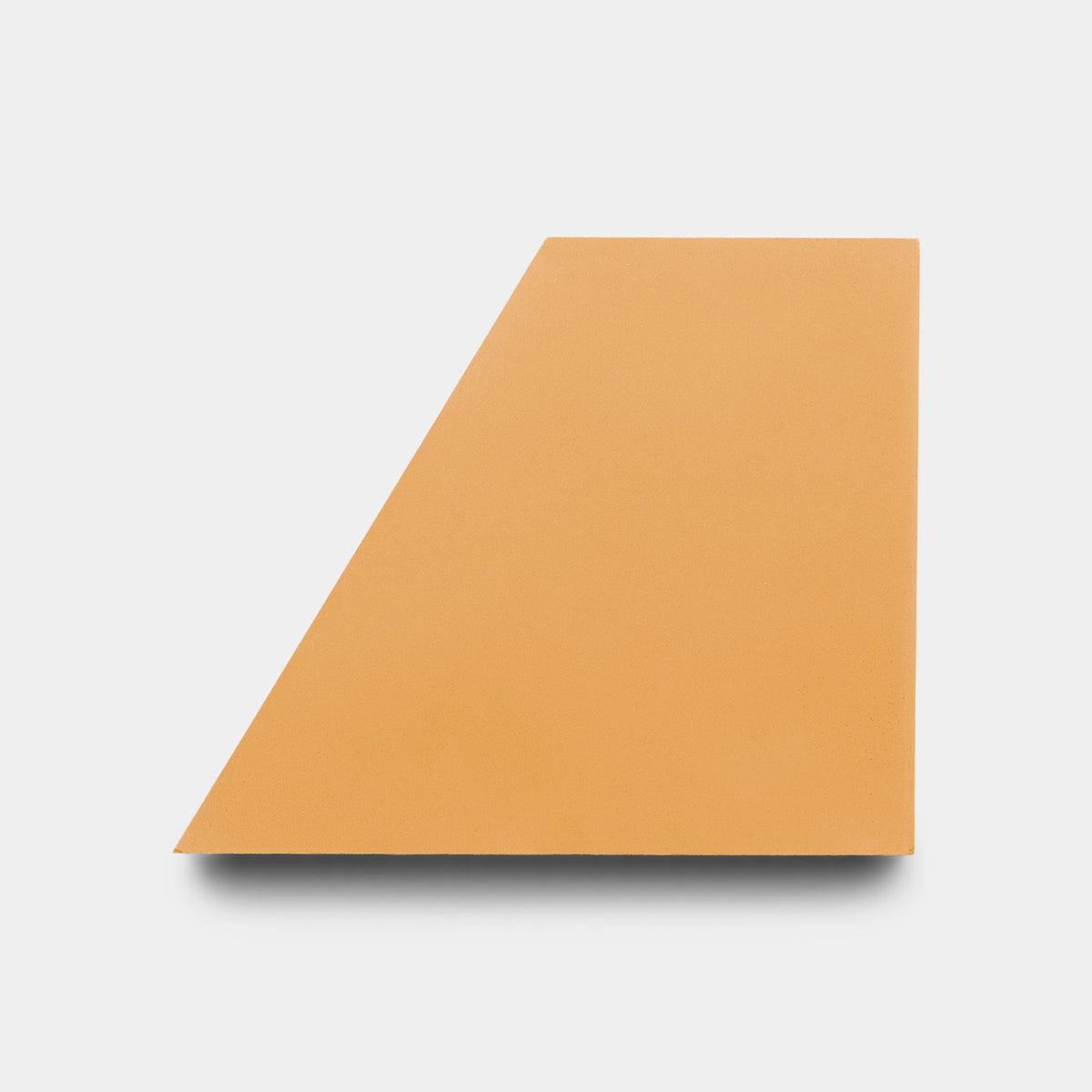 A flat, orange geometric shape with a slanted edge rests on white, casting a slight shadow—echoing the handmade tile aesthetic of Zia Tile’s Derby Ginger + Bone sample.