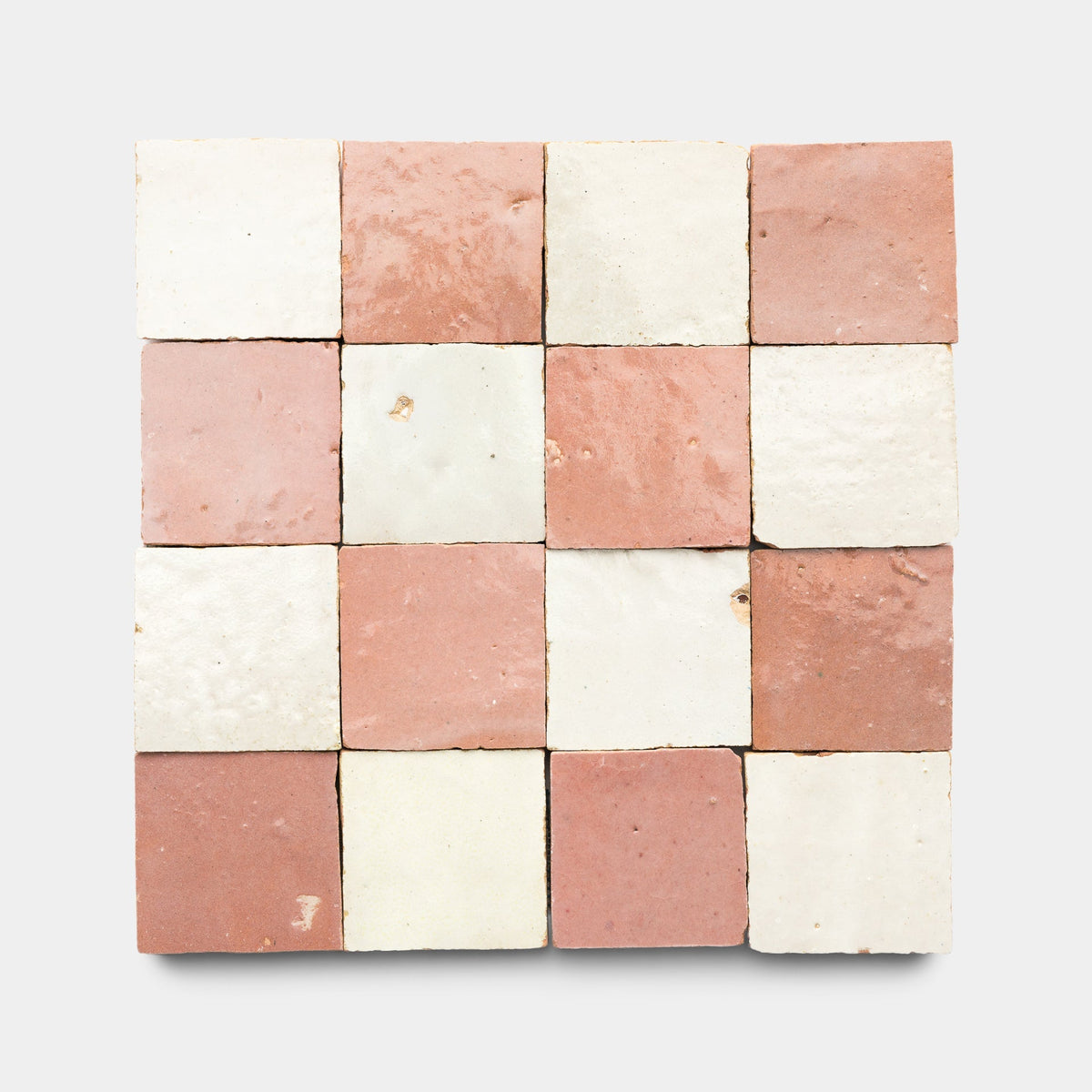 A 4x4 grid of Zia Tile’s Desert Bloom + Casablanca Checkerboard ceramic tiles, alternating light pink and off-white samples, arranged on a plain light gray background.