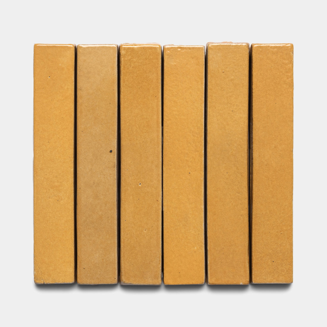 Six Dorado Mini Bar tiles by Zia Tile, featuring a yellowish-brown rectangular design, are arranged vertically side by side on a plain white background.