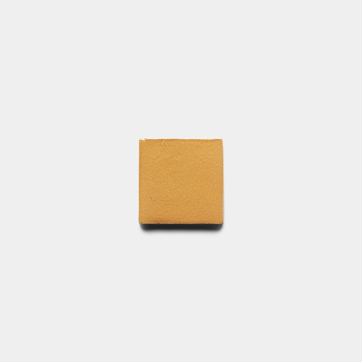 A single Dorado 4x4 Square tile sample by Zia Tile, light brown and square, is centered on a plain white background, resembling a handmade cement tile.