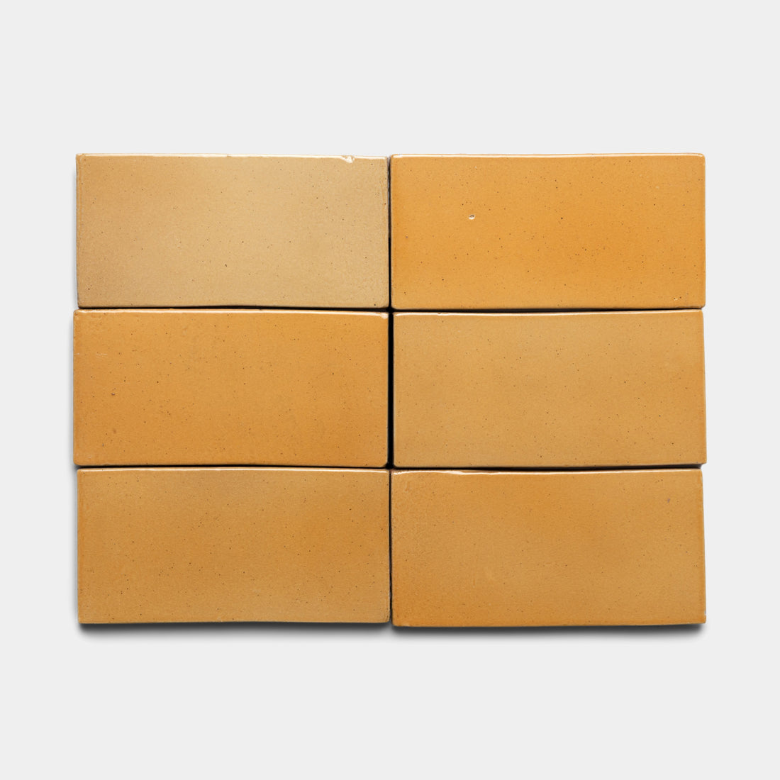 Six Dorado 4x8 Rectangle bricks by Zia Tile are arranged in two rows of three against a plain white background. The bricks display subtle shade variations, from light tan to deeper ochre.