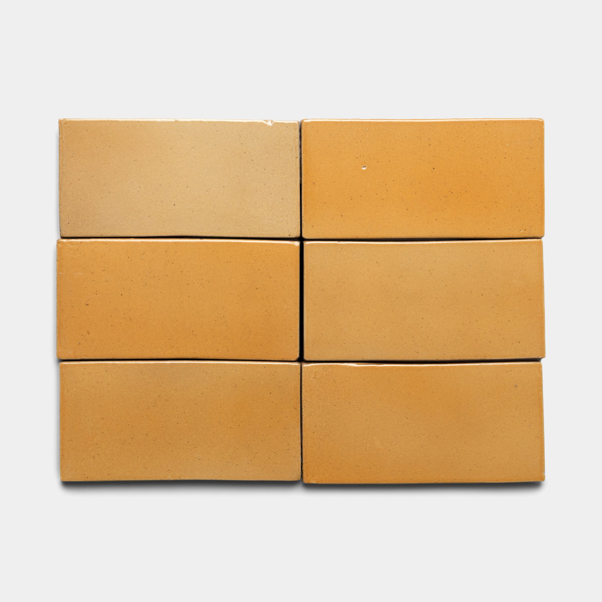 Six Dorado 4x8 Rectangle bricks by Zia Tile are arranged in two rows of three against a plain white background. The bricks display subtle shade variations, from light tan to deeper ochre.