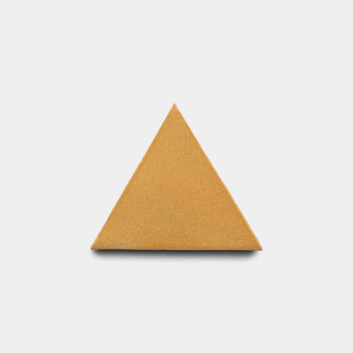 A single Dorado Triangle tile by Zia Tile, in a plain light brown color and triangular shape, is centered on a plain white background.