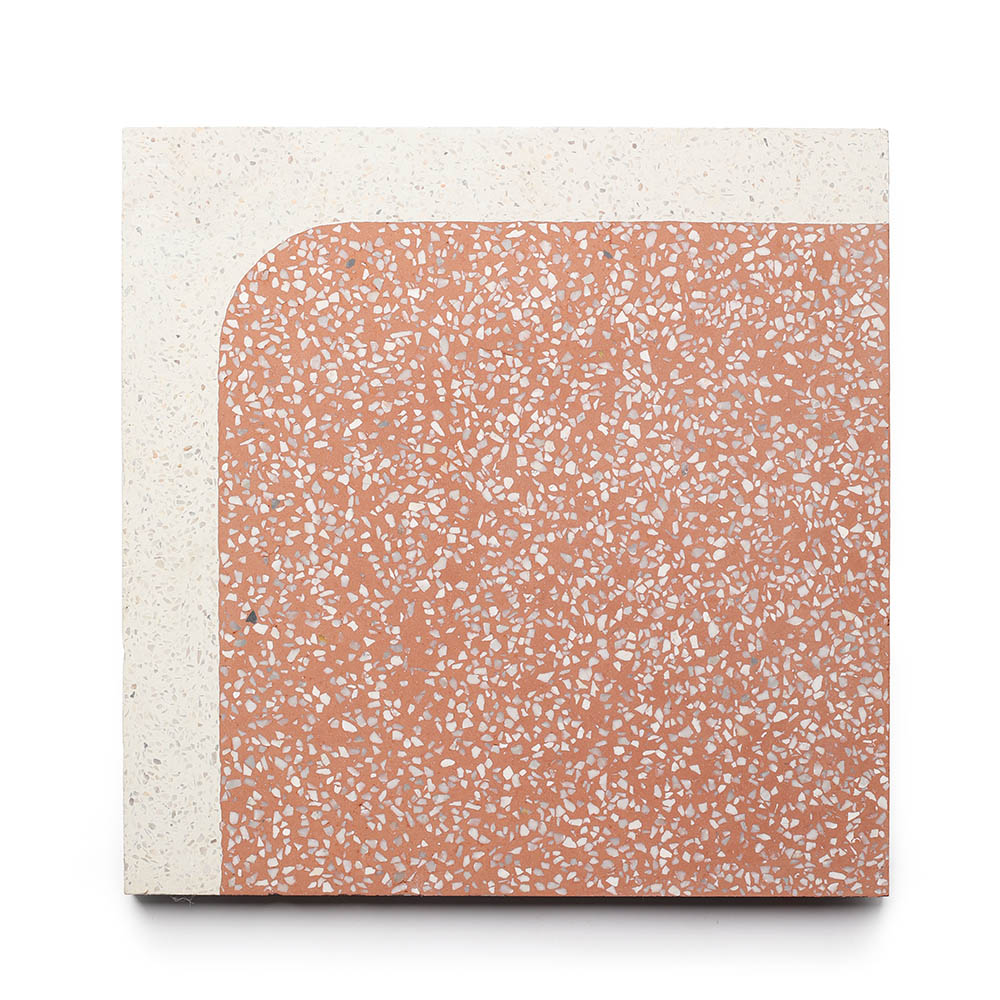 The Draper Rust 12x12 tile sample from Zia Tile features a terracotta terrazzo base with white stone chips, showcasing an L-shaped white border along the top and left edges and a rounded corner.