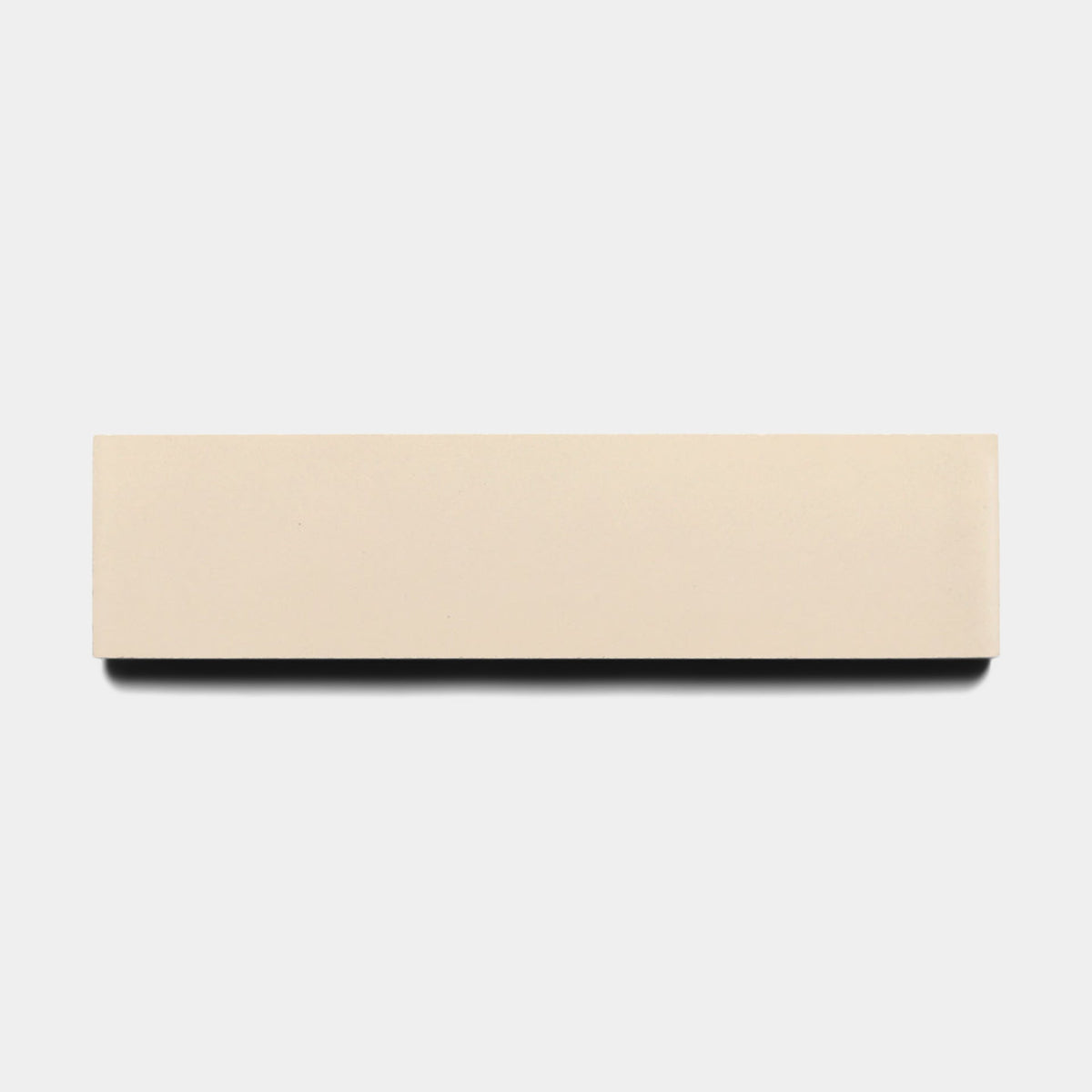 The Dune 2x8 sample from Zia Tile, a rectangular beige tile resembling a classic eraser, is displayed against a plain white background with a subtle shadow below.
