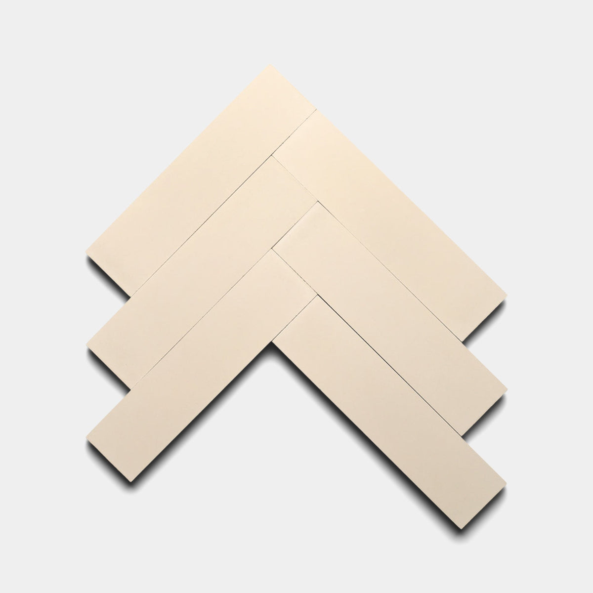 Five rectangular cream-colored Dune 2x8 samples from Zia Tile are arranged in a herringbone pattern on a plain, light gray background, highlighting the tile's elegant appearance.