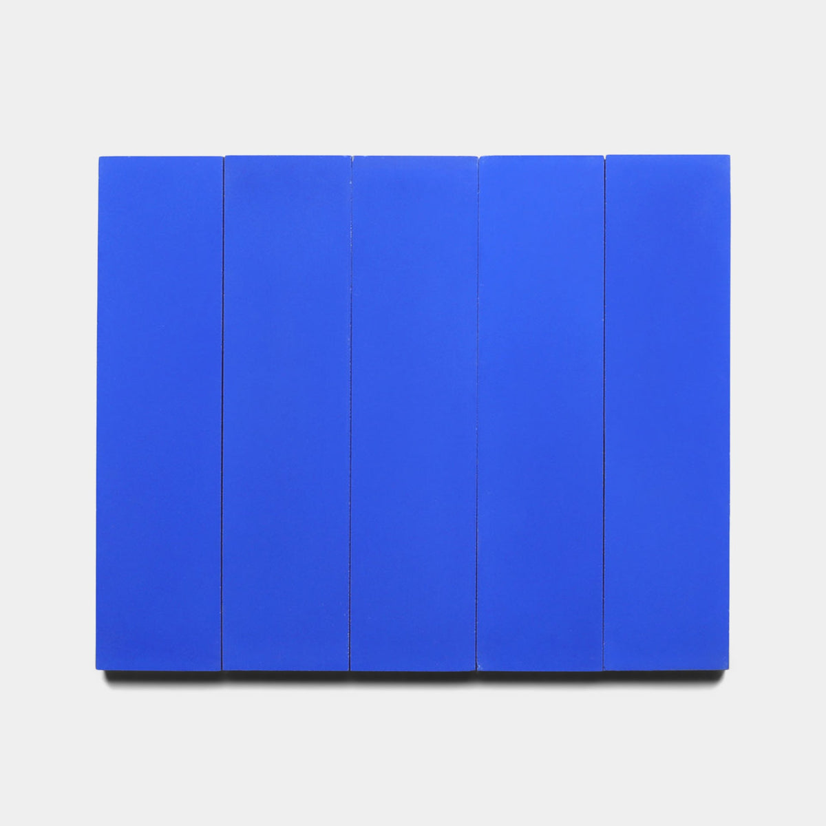 Five Elemental Blue 2x8 samples by Zia Tile are aligned side by side against a plain white background, forming a minimalist and geometric composition.