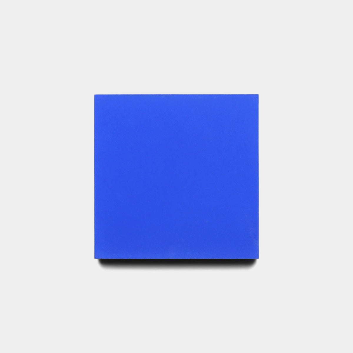 A single Elemental Blue 4x4 Sample tile from Zia Tile is centered on a white background with a soft shadow, offering a sleek and modern display.