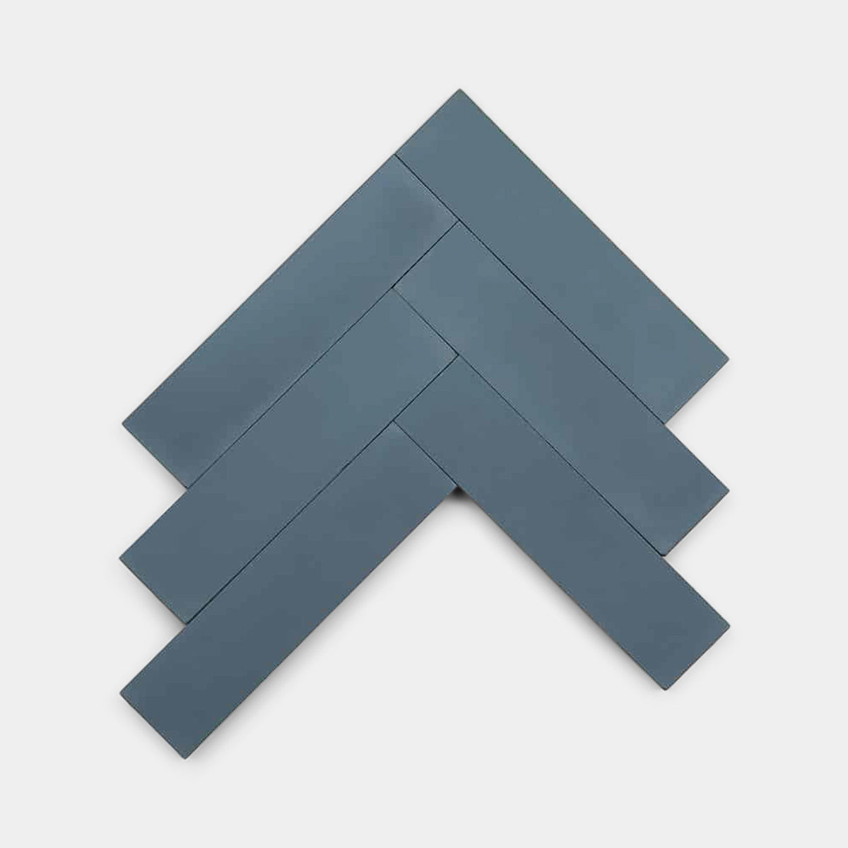 Five Elemental Blue 2x8 tiles by Zia Tile are arranged in a herringbone pattern on a white background, ideal as a sample display.