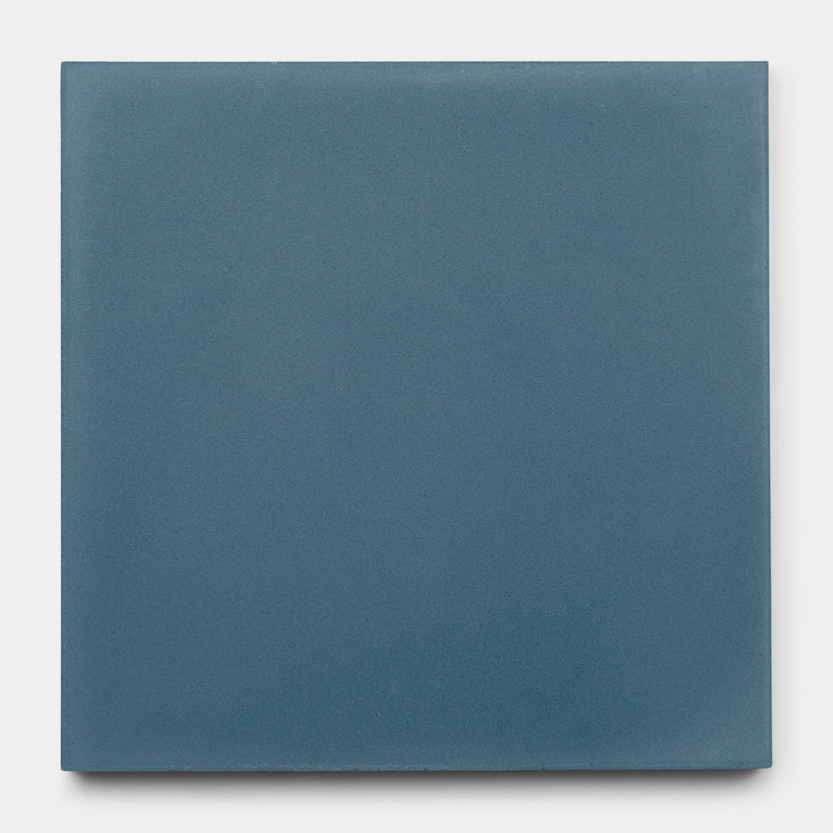 A sample of Zia Tile’s Elemental Blue 8x8 tile is shown in a matte, solid blue shade against a light gray background.