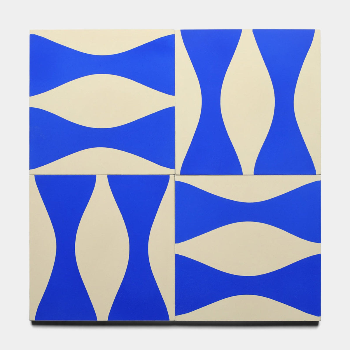 Four Enzo Elemental Blue 8x8 tiles by Zia Tile, each with a cream base and curved royal blue waves, arranged in a grid to showcase the dynamic geometric pattern in this sample.