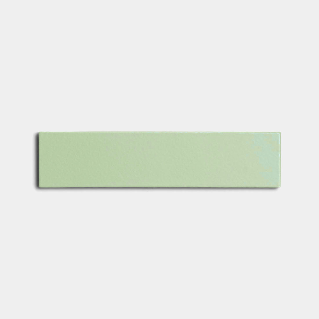 The Eucalyptus 2x8 rectangular light green ceramic tile by Zia Tile, featuring a glossy finish, is centered on a plain white background.