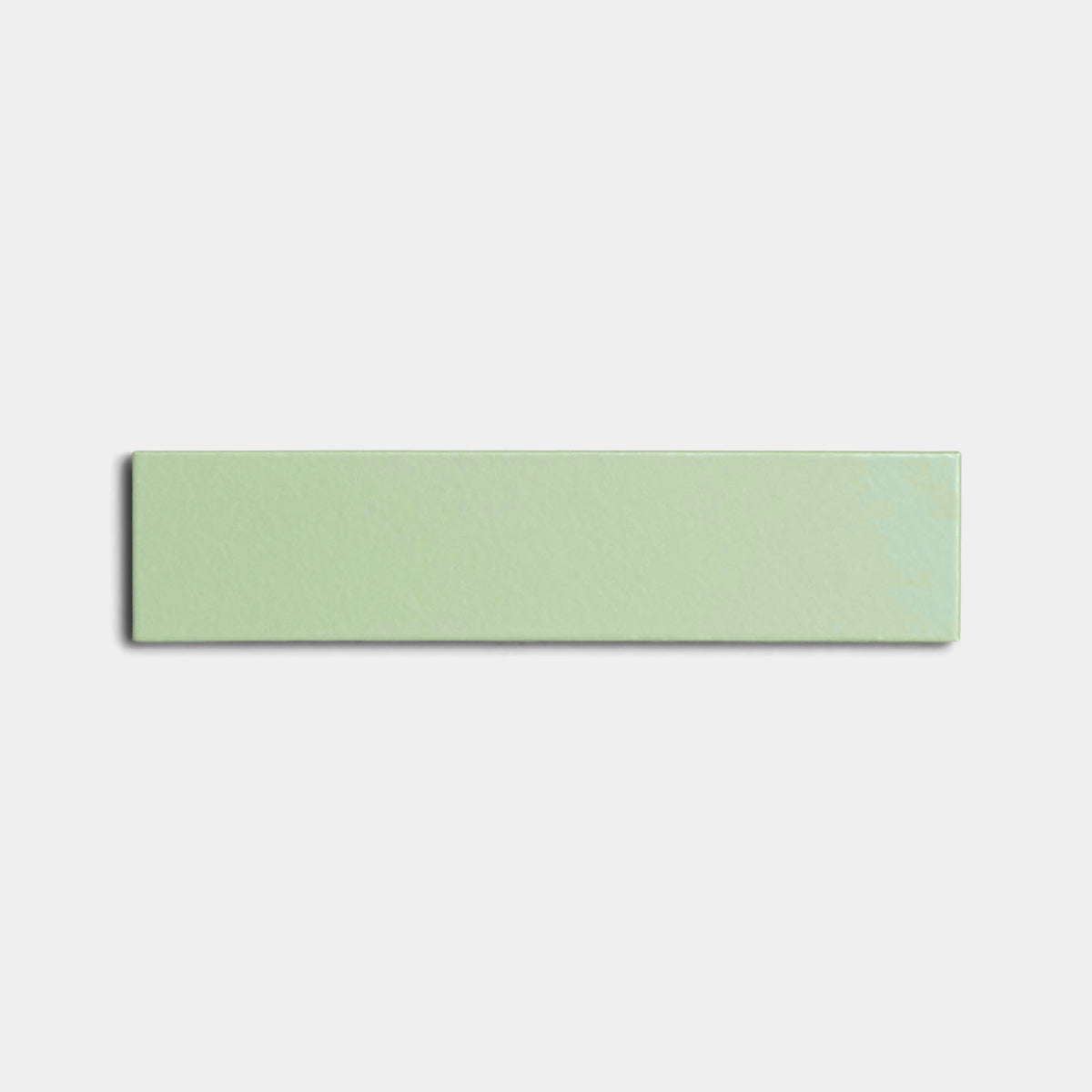 The Eucalyptus 2x8 rectangular light green ceramic tile by Zia Tile, featuring a glossy finish, is centered on a plain white background.