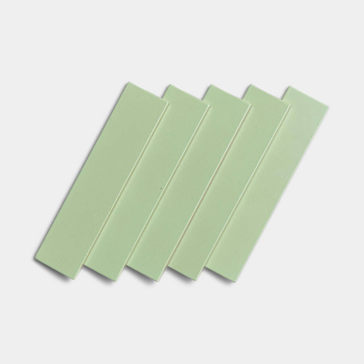 Five Eucalyptus 2x8 tiles by Zia Tile, in light green matte ceramic, are arranged in a slightly overlapping fan pattern on a white background.