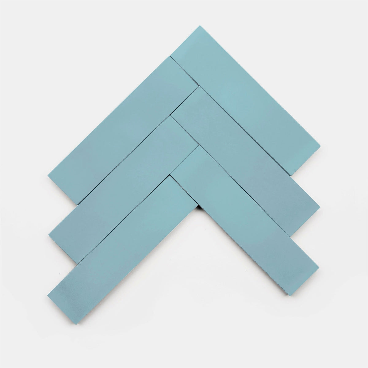 Five rectangular Everest 2x8 blue cement tiles from vendor-unknown are arranged in a herringbone pattern on a white background, highlighting their distinct craftsmanship.