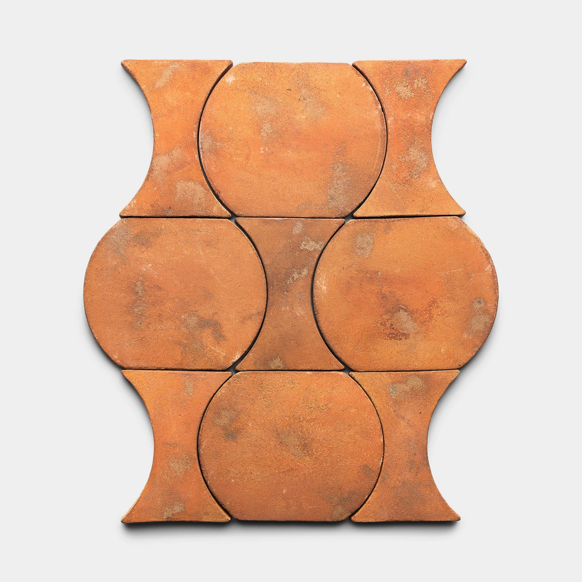 Six Oaxaca + Fired Earth samples from Zia Tile are arranged in a rectangular grid, showcasing a warm earthy orange tone with a repeating geometric pattern of circular and hourglass shapes.