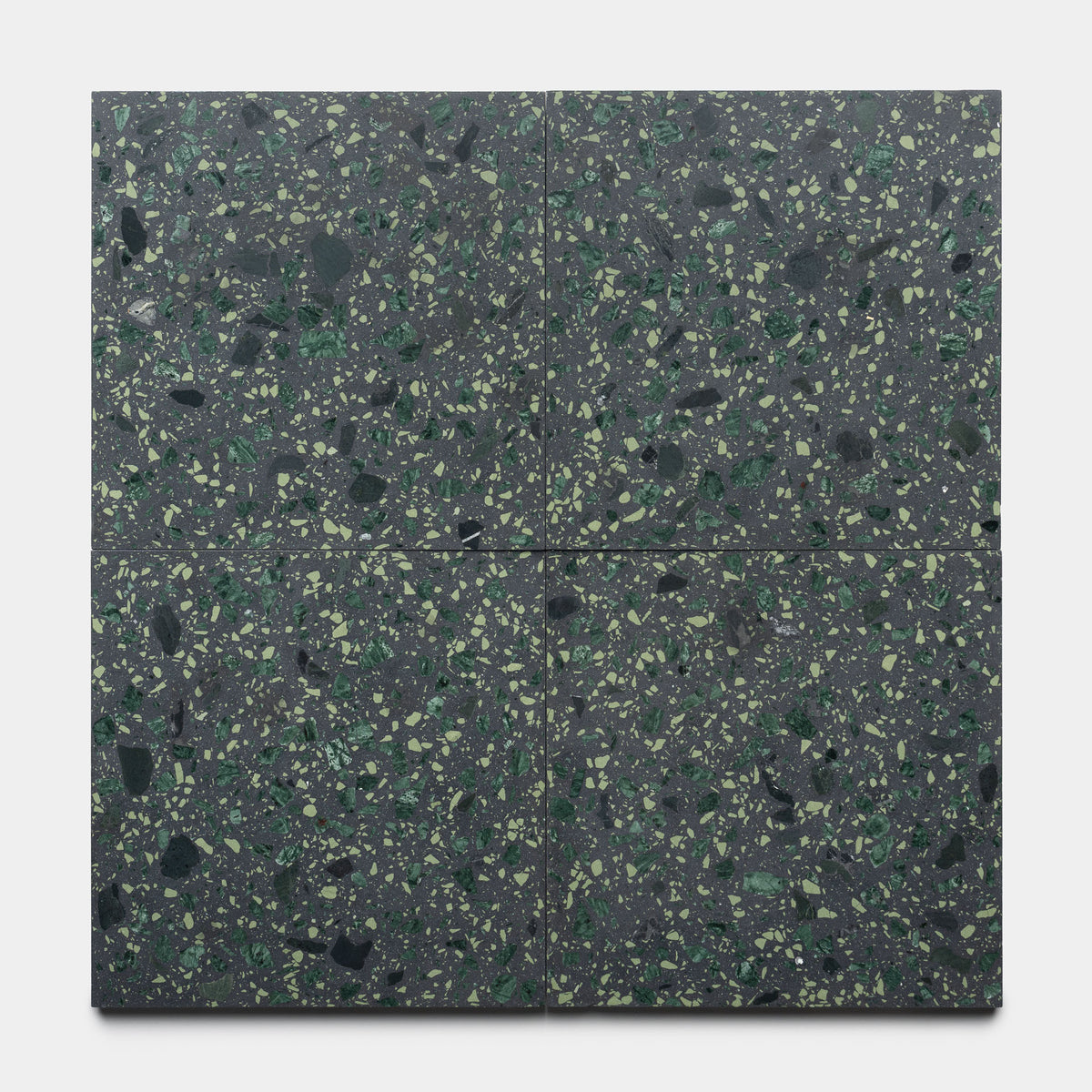 Four Flagstaff 12x12 tiles by Zia Tile, featuring a dark green terrazzo with green, black, and light green speckles, are arranged in a square grid on a plain light background.