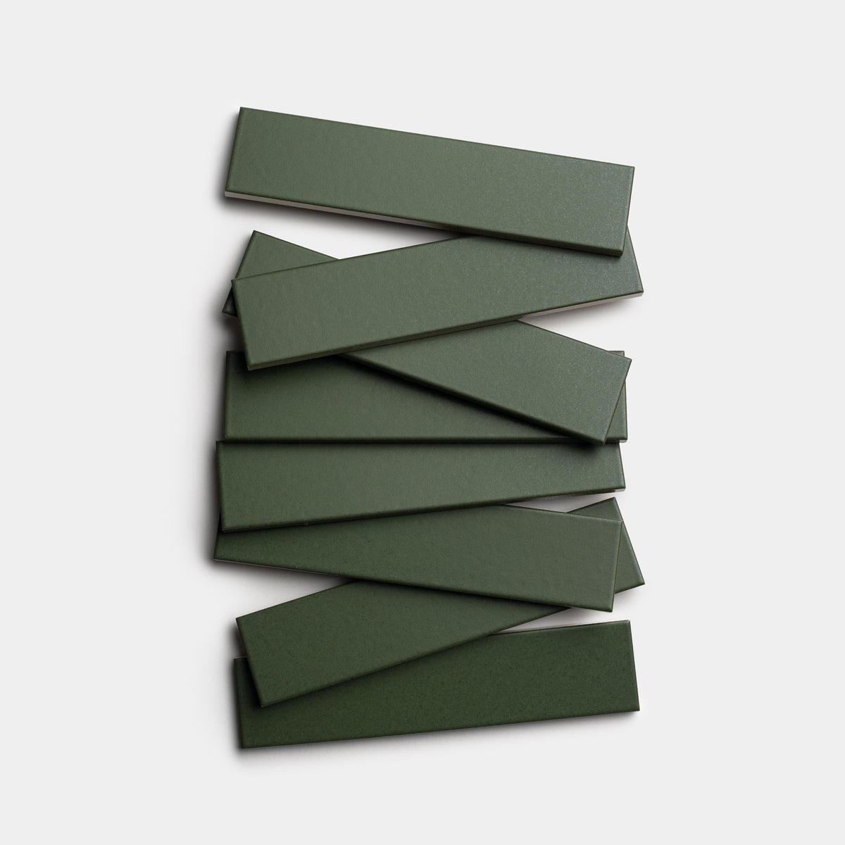 Eight Fraser 2x8 rectangular ceramic tiles by Zia Tile, in forest green, are arranged in a staggered, overlapping stack against a white background.