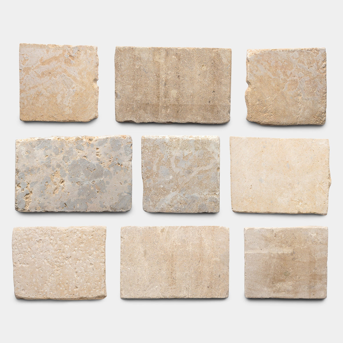 Nine French Cobblestone sample tiles from Zia Tile are arranged in three rows on a plain white background, each showing unique beige, tan, and light gray textures.