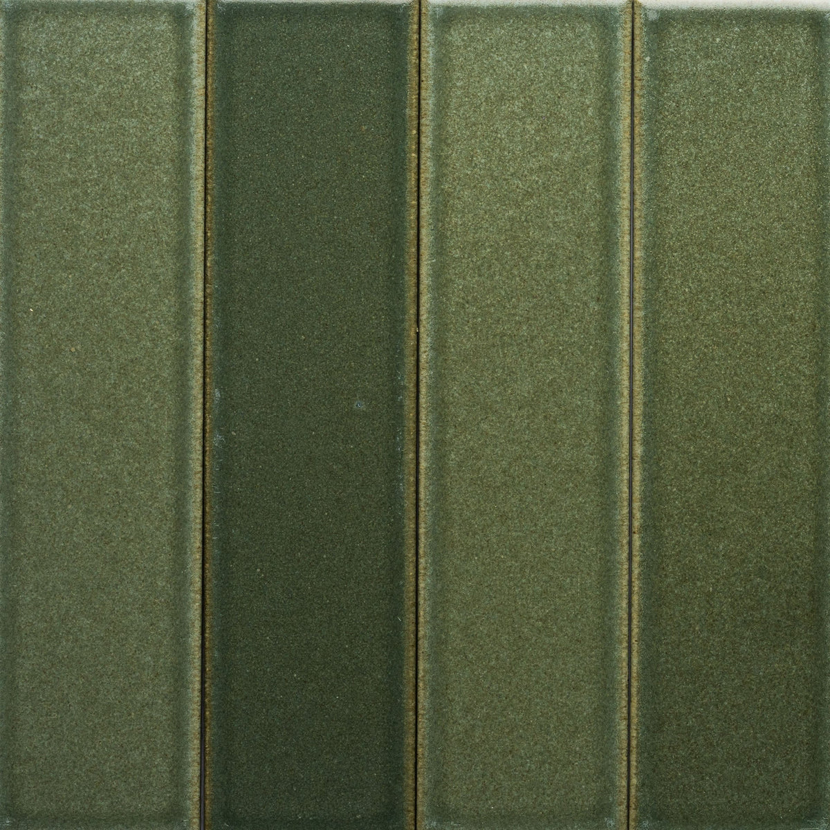 Close-up of four Frogtown + Flat, Sample tiles by Zia Tile in varying green shades. The vertical, rectangular tiles have a subtle sheen and textured surface, aligned closely with thin seams.