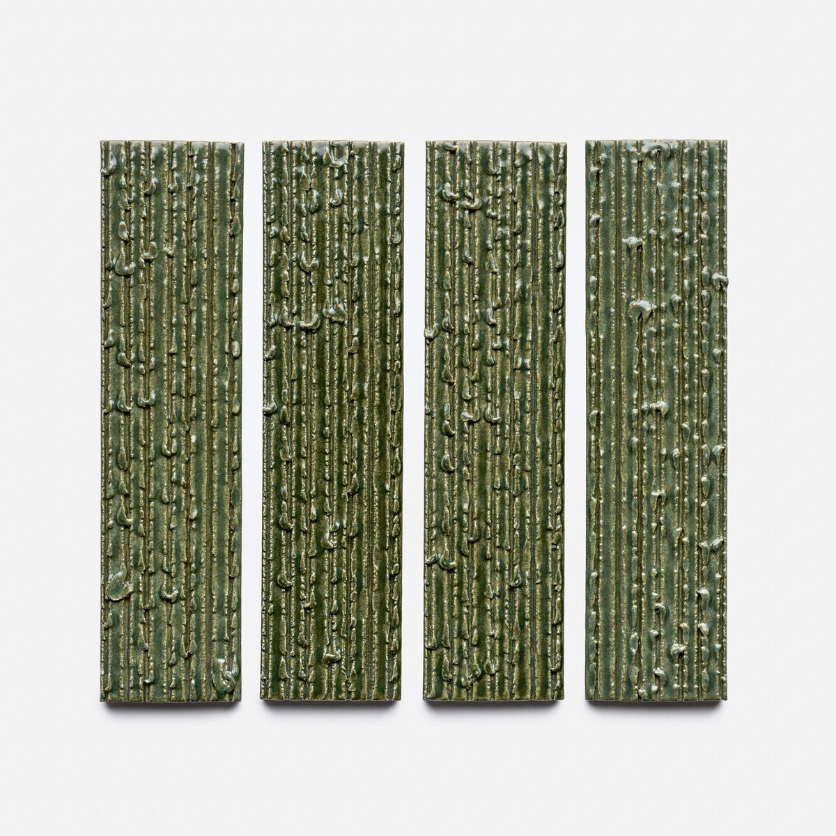 Four Frogtown + Furrowed sample tiles by Zia Tile are arranged side by side on a white background. Each green tile features a vertical, rectangular shape and raised, bark-like textured lines.
