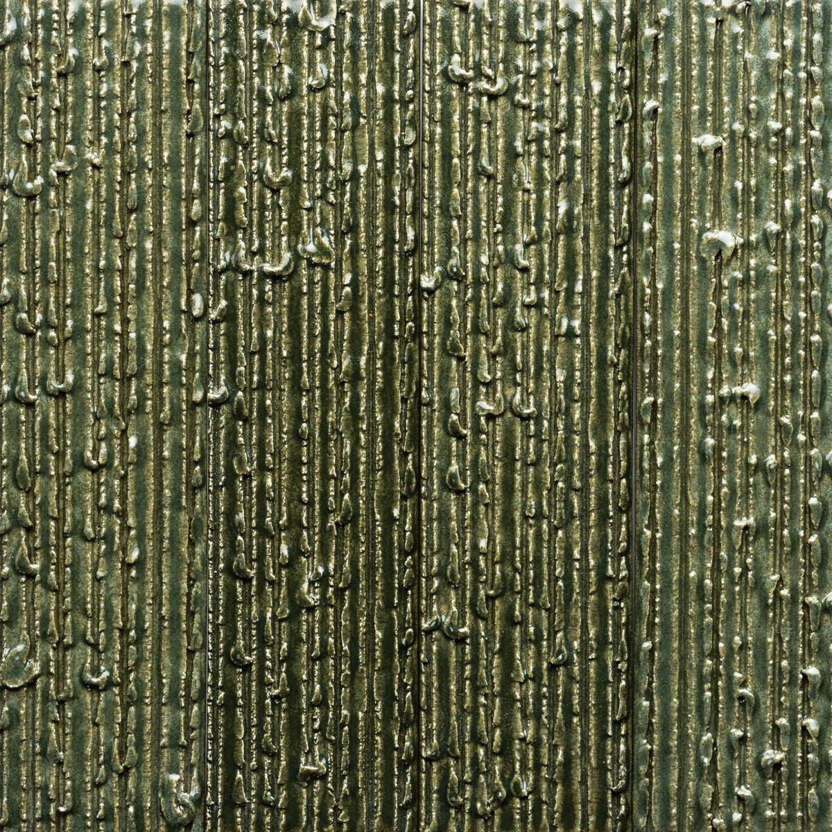 Close-up of Frogtown + Furrowed, Sample by Zia Tile shows a textured surface with metallic green vertical ridges and raised, uneven lines resembling drips, creating an abstract, industrial look.