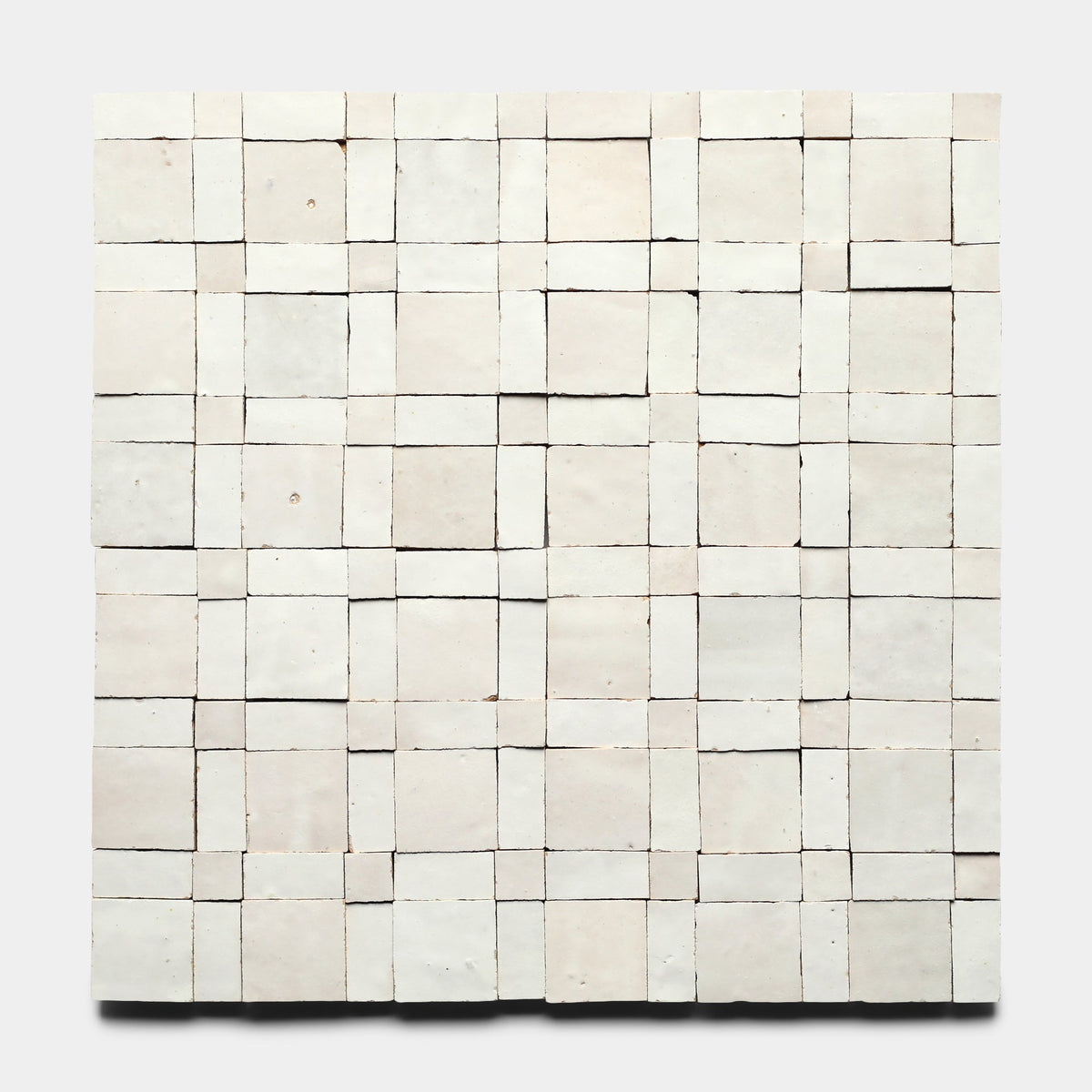 Gambit 1, Sample by Zia Tile features a square grid of off-white handmade tiles with uneven texture and slight misalignments in a woven pattern, set against a plain light background.