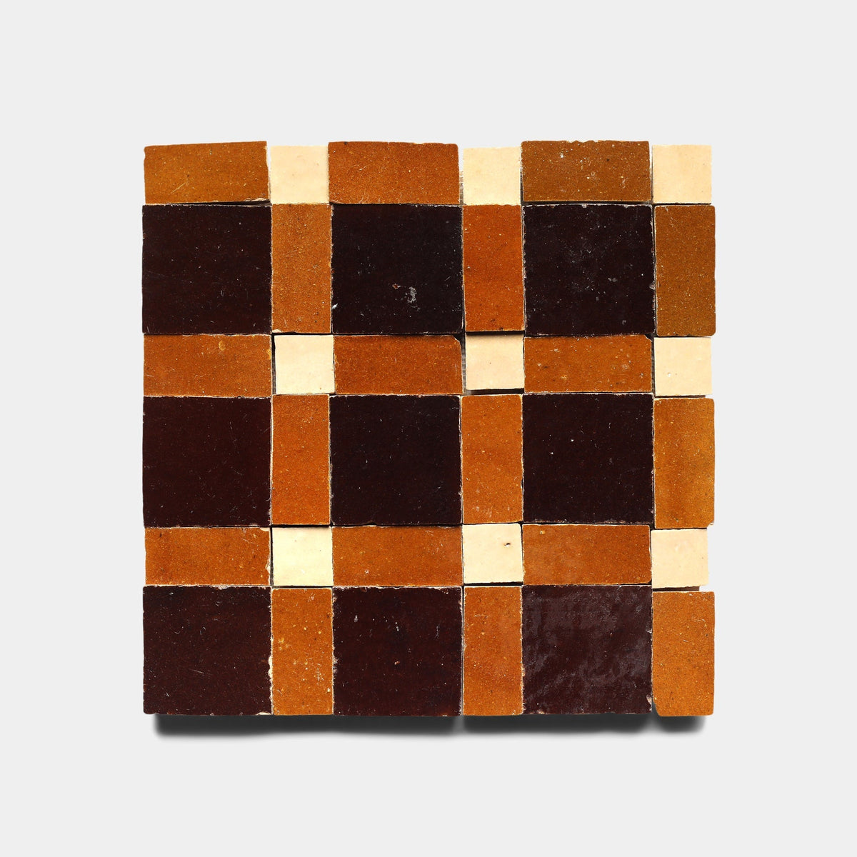 Gambit 5, Sample by Zia Tile features square handmade tiles in a checkerboard pattern with dark brown, burnt orange, and cream on a light gray background.