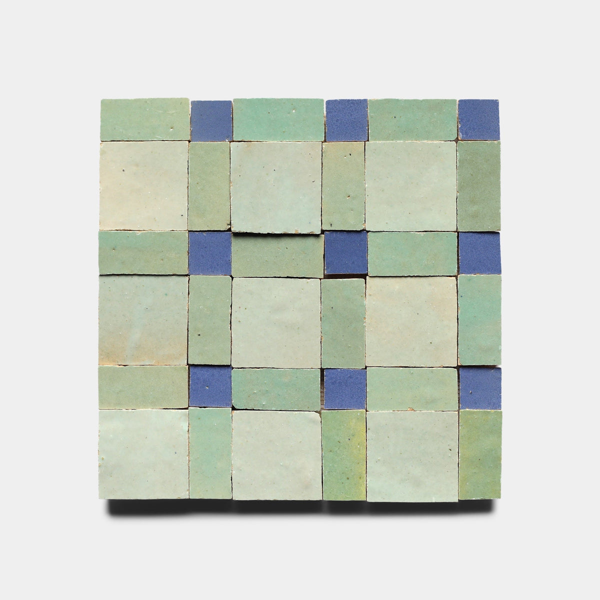 Gambit 7 by Zia Tile features a square mosaic of green and light blue handmade tiles, accented with smaller dark blue tiles arranged in a grid on a white background.