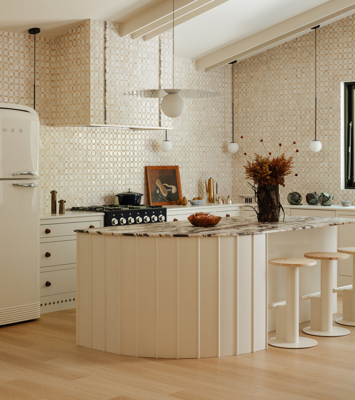 Kitchen island with a curved, paneled base and marble countertop, accented by a checkerboard-patterned backsplash of Gambit 2 tiles by Zia Tile.