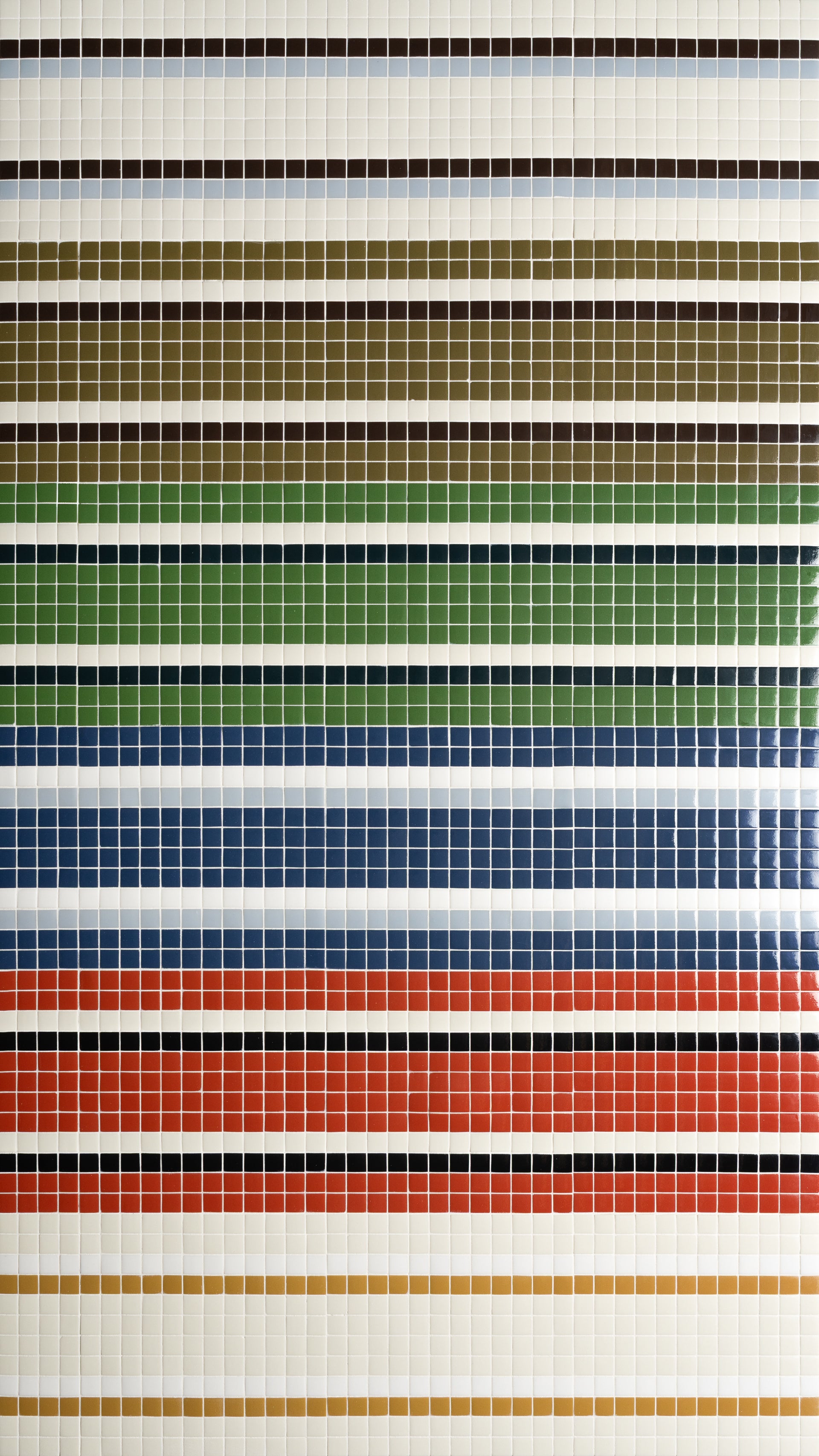 A wall covered in small square tiles arranged in horizontal stripes of various colors, including black, brown, green, blue, red, and beige, creating a vibrant, orderly pattern.