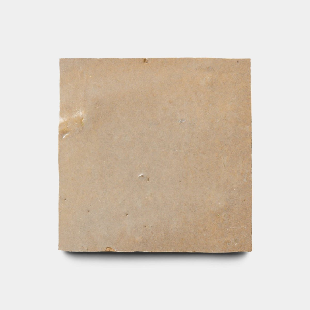A single Glazed Earth 2x2 sample from Zia Tile, a plain square of brown glazed tile with minimal markings, showcases simple elegance against a white background.