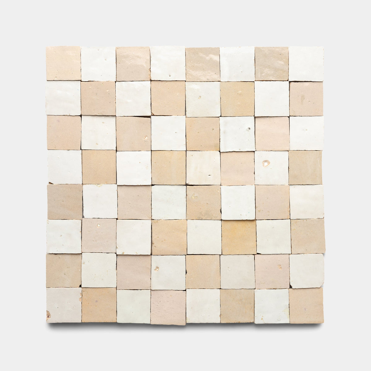 The Glazed Earth + Casablanca Checkerboard sample by Zia Tile features a square grid of handmade, uneven tiles in off-white and light beige, arranged in a checkerboard pattern on a plain background.