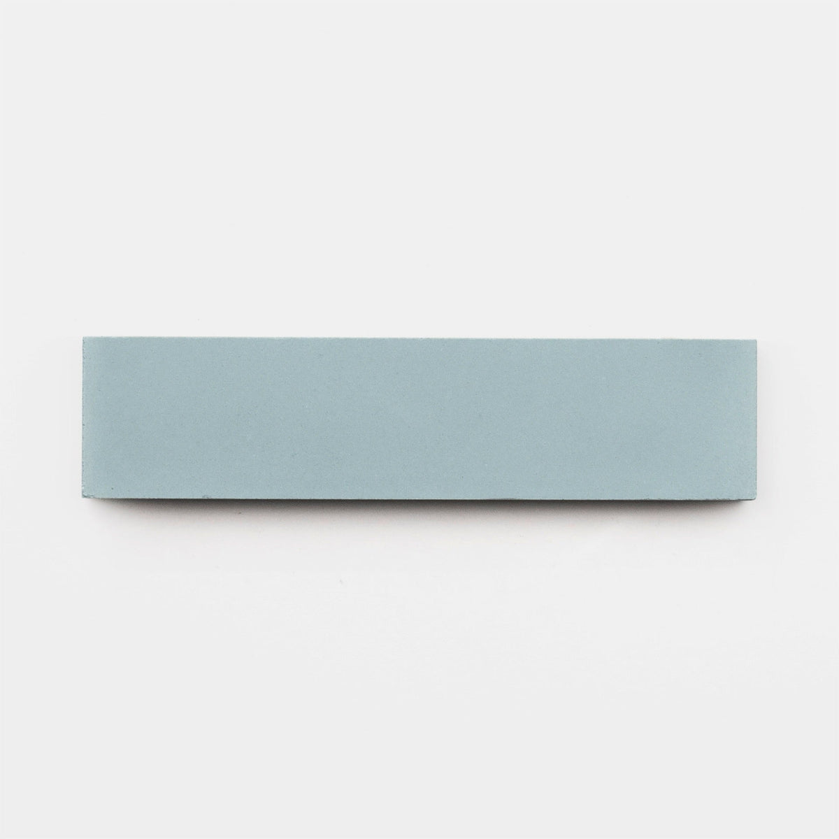 A rectangular, light blue Hailstone 2x8 tile sample by vendor-unknown rests on a plain white background, reminiscent of a handmade tile from Zia Tile.