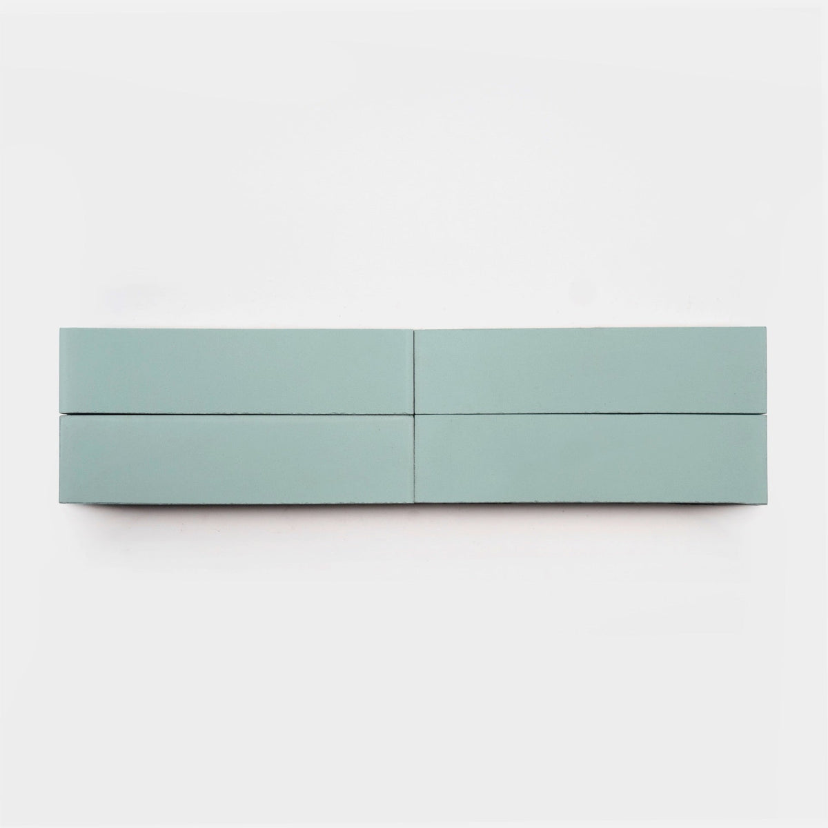 A minimalist, light blue Hailstone 2x8 cement tile sample by vendor-unknown, rectangular and split into four equal sections, is displayed in a single row against a plain white background.