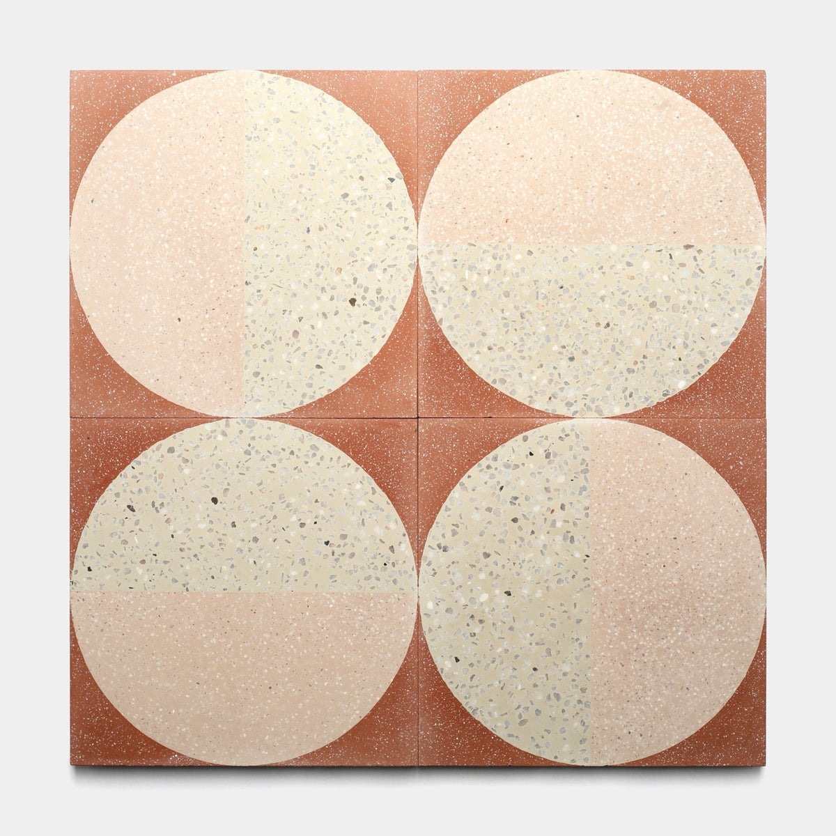 Four handmade Highball Jaipur Pink 12x12 cement tiles by Zia Tile arranged in a grid, each displaying a bold cream and beige terrazzo circle on a reddish-brown background, showcasing geometric elegance and expert craftsmanship.