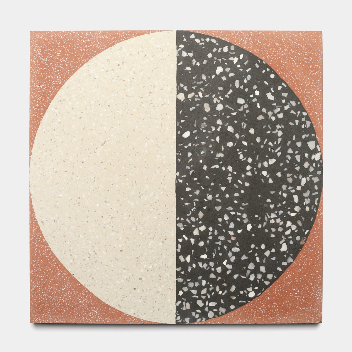 The Zia Tile Highball Rust 12x12 sample is a square handmade tile with a large circle split vertically: cream with light specks on the left, black with white specks on the right, set on a terracotta background dusted with tiny white flecks.