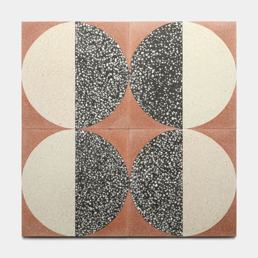Four Zia Tile Highball Rust 12x12 tiles are arranged in a grid, each displaying a vertically split circle—one half speckled black, the other cream—against a reddish-brown background for a bold geometric effect.