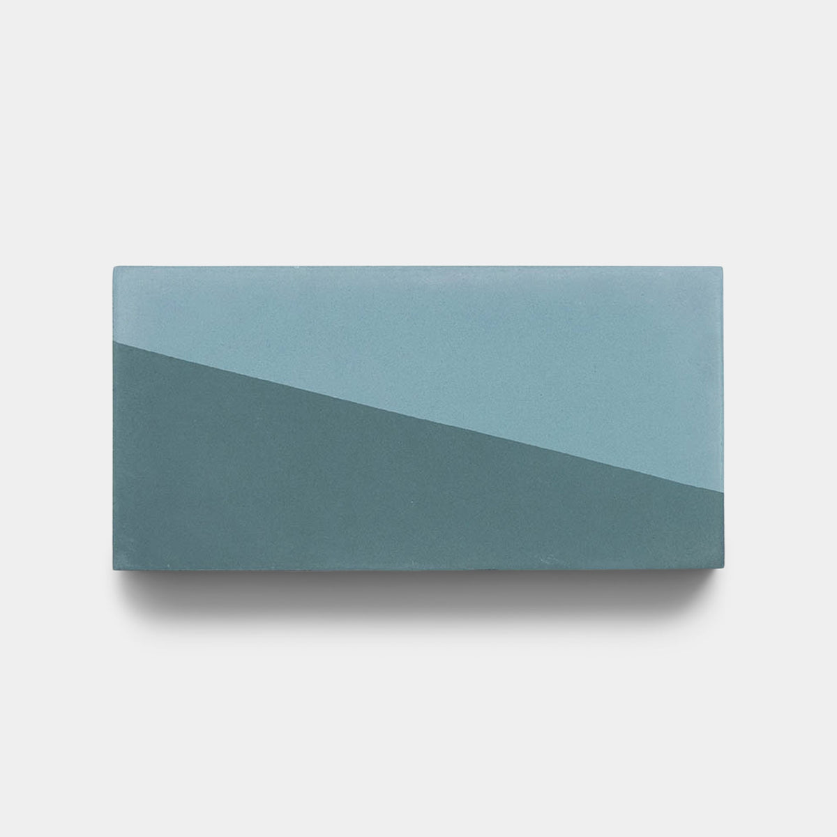 The Incline Hyannis 4x8 sample by Zia Tile is a rectangular handmade tile in two blue shades, with a diagonal split separating the lighter top left from the darker bottom right, displayed on a plain light background.