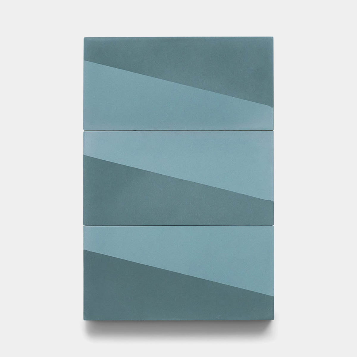 The Incline Hyannis 4x8 sample by Zia Tile features three handmade rectangular tiles stacked vertically, each with diagonal blue stripes forming a continuous geometric design on a light gray background.