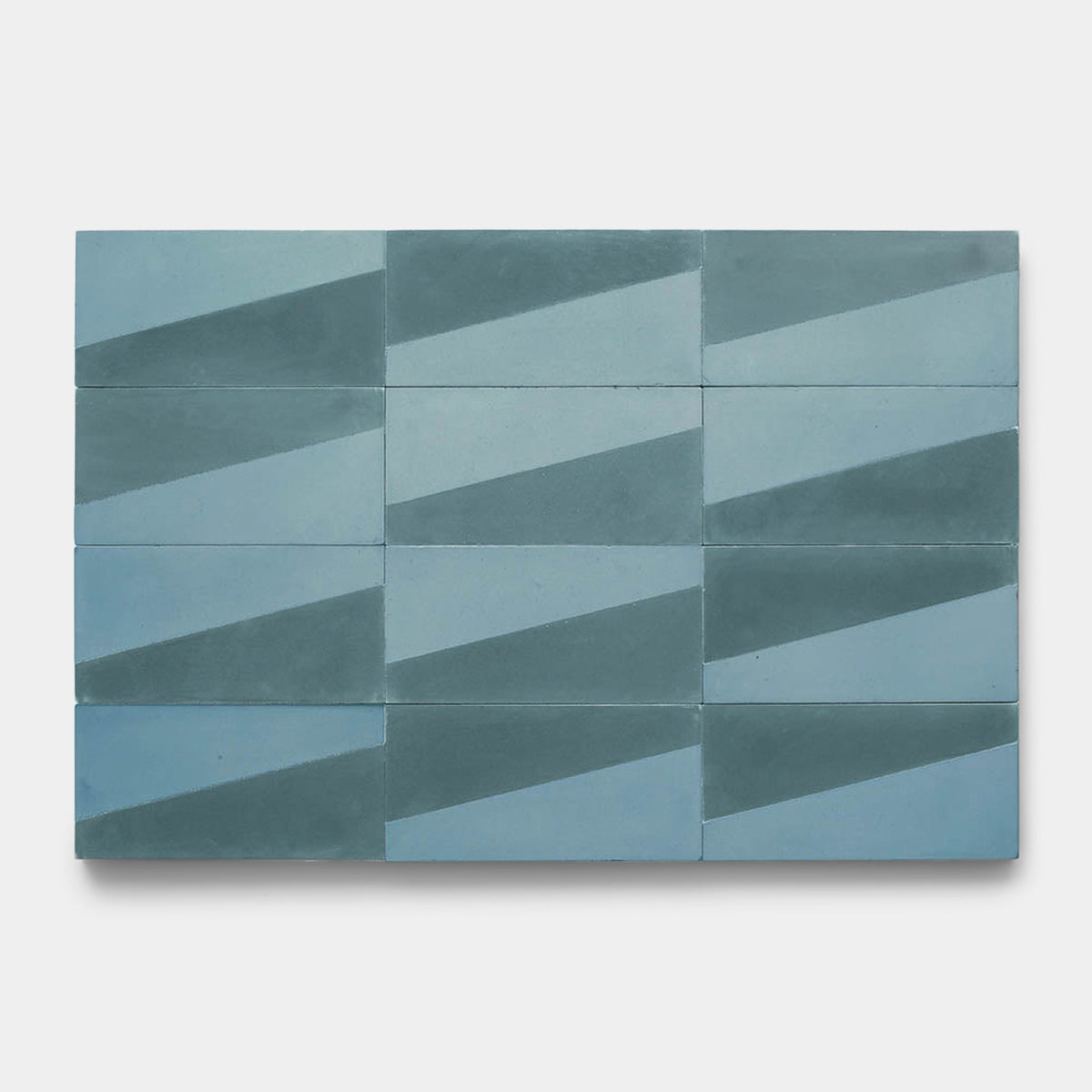 A rectangular layout of twelve Incline Hyannis 4x8 Zia Tile samples features blue and teal tiles, each with a diagonal color split forming a bold geometric zigzag pattern.