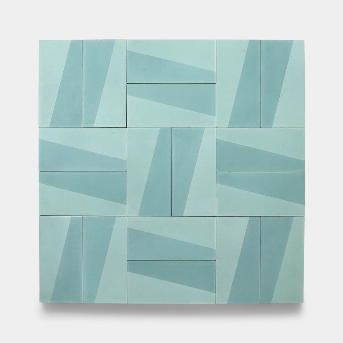 The Incline Salvia 4x8 sample by Zia Tile features a grid of geometric cement tiles in light blue and teal, each with diagonal shapes that form an abstract, repeating surface pattern.