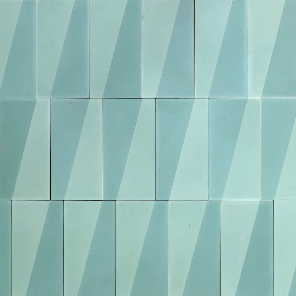 A grid of Zia Tile Incline Salvia 4x8 cement tiles, featuring rectangular pale blue shapes with diagonal light and dark blue stripes, forms a repeating geometric pattern across the surface.