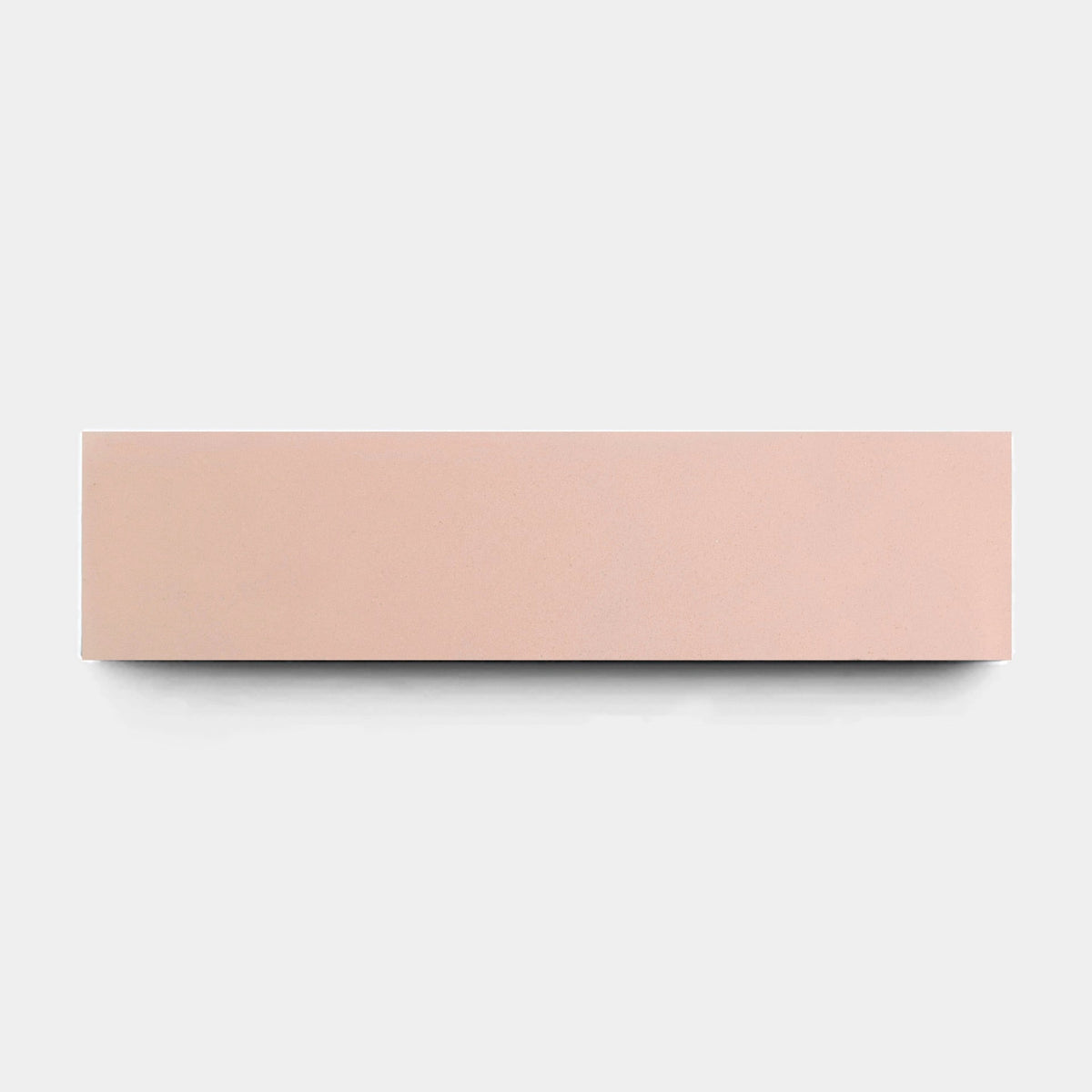 A Jaipur Pink 2x8 sample tile by vendor-unknown, rectangular and light pink, is centered on a plain light gray background, showcasing its smooth and simple handmade appearance.