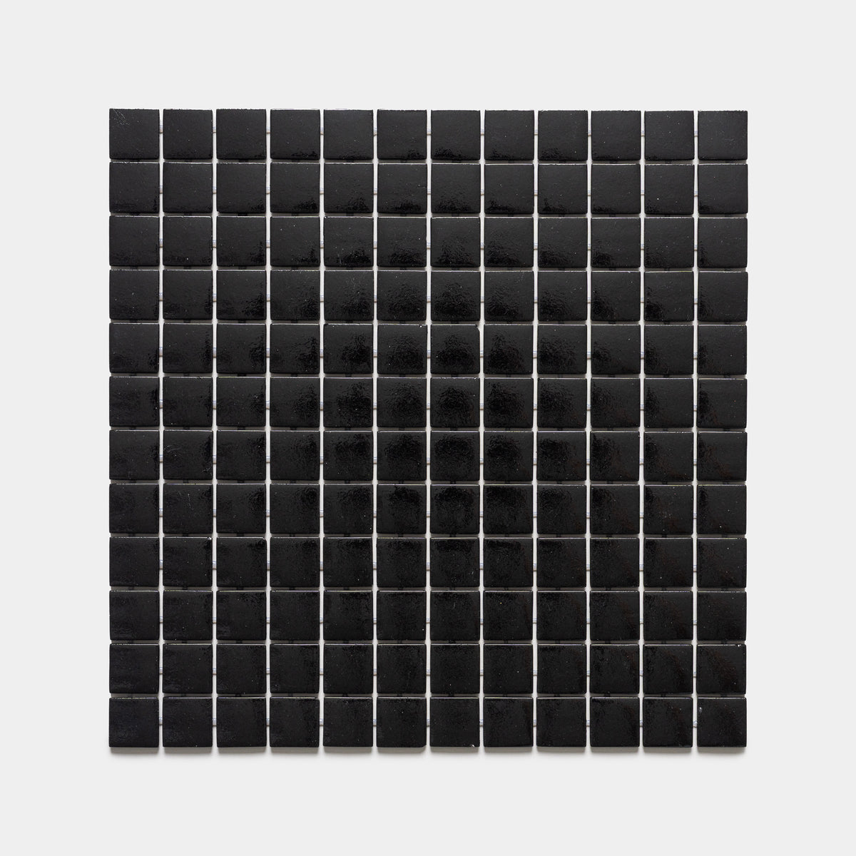 A grid of evenly spaced Jet Black 1x1 tiles by Zia Tile, each with a glossy finish, is arranged on a white background to create a rectangular mosaic pattern.