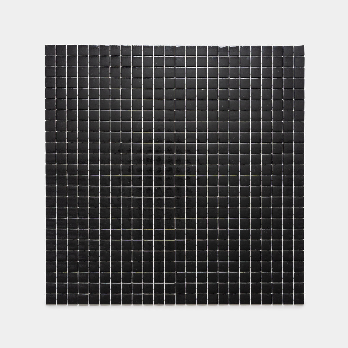 The Jet Black 1x1 by Zia Tile features small black squares arranged in neat rows and columns on a white background, enhanced by a subtle shadow or gradient that forms a faint dark circle at the center.