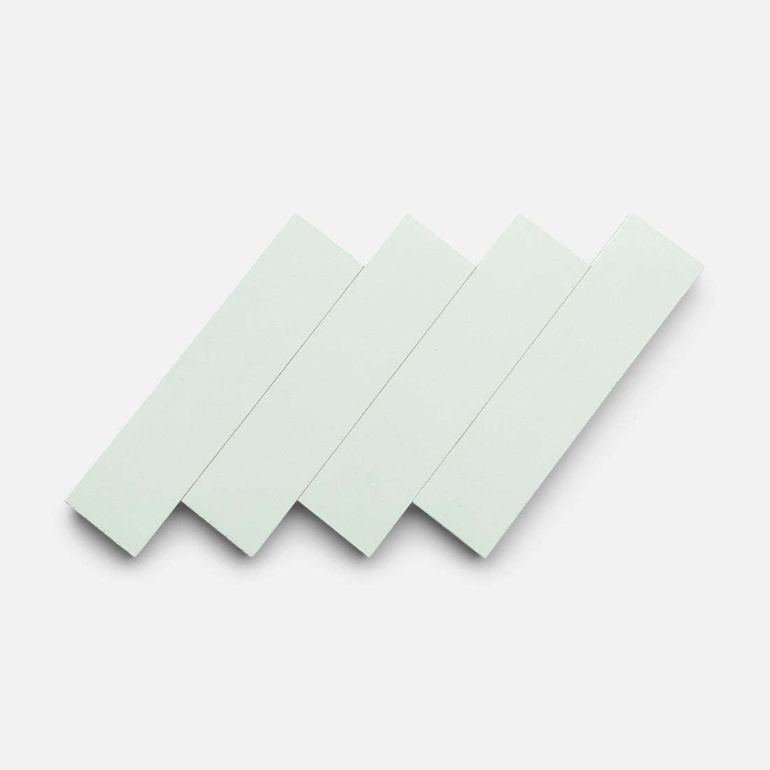 Four Julep 2x8 rectangular white tiles by Zia Tile are arranged diagonally in a staggered, overlapping pattern against a plain light background.