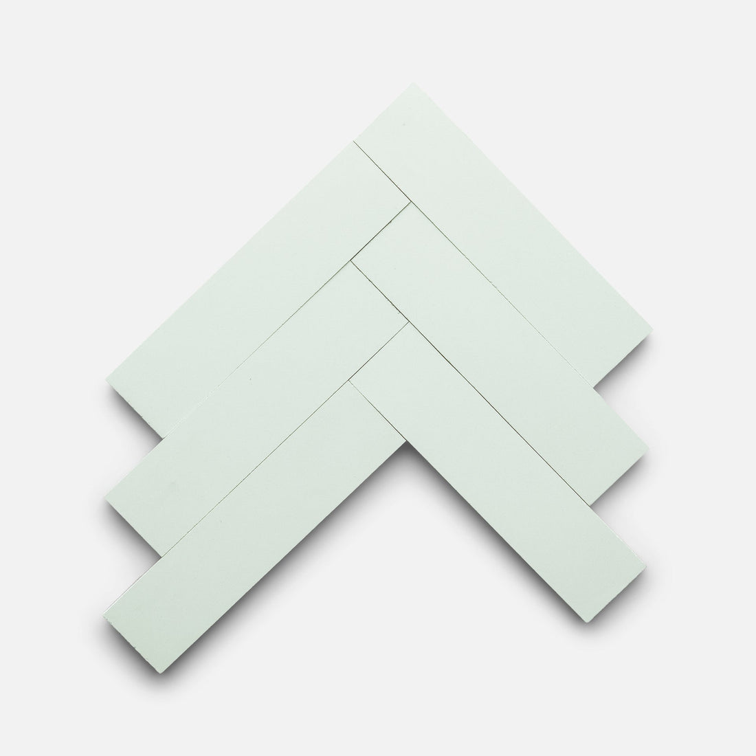 Five Julep 2x8 tiles from Zia Tile, rectangular and white, are arranged in a herringbone pattern on a plain white background.