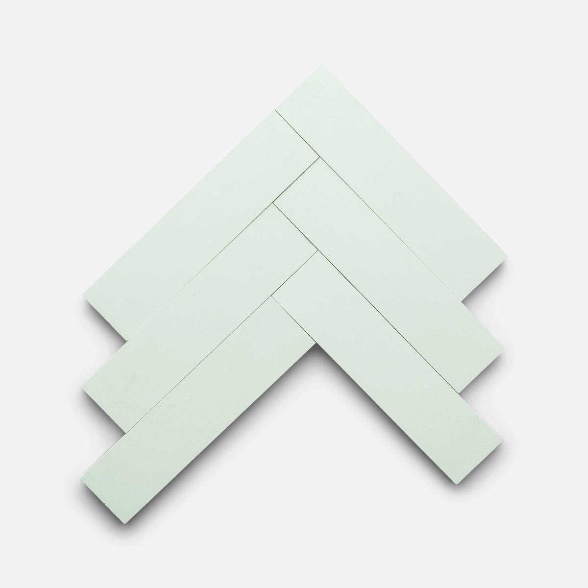 Five Julep 2x8 tiles by Zia Tile are arranged in a herringbone pattern on a plain white background, overlapping at angles to create a zigzag design.
