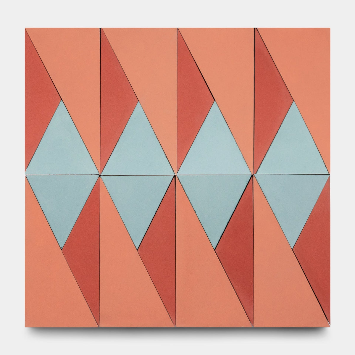 The Kepler Set One, Sample by Zia Tile features a grid of salmon pink, red, and light blue triangles and diamonds in geometric symmetry, evoking the look of artisanal handmade cement tile.